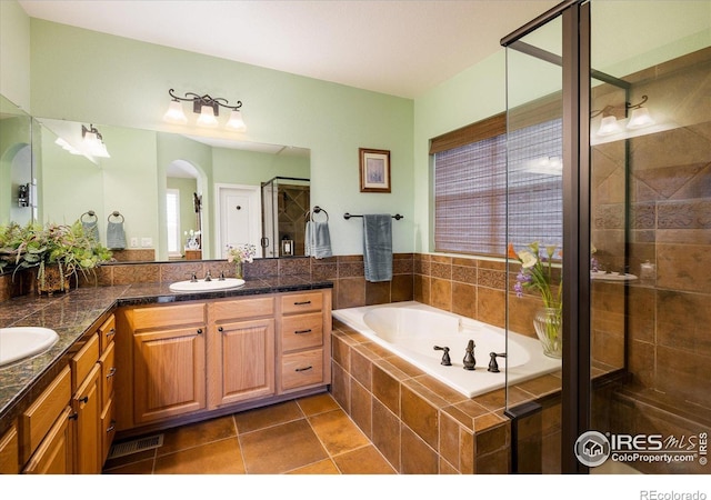 full bath with double vanity, a sink, a shower stall, tile patterned floors, and a bath