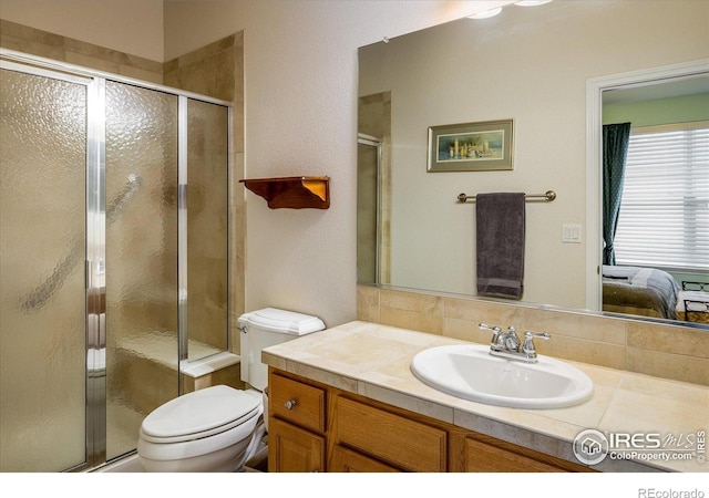 bathroom featuring connected bathroom, vanity, a shower stall, and toilet