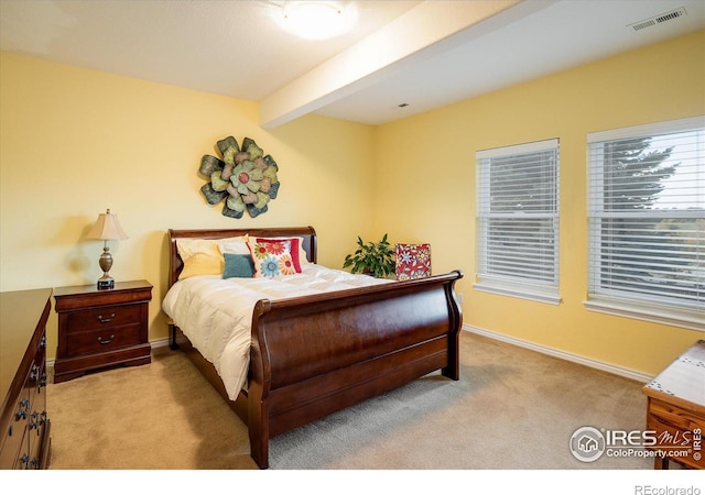 bedroom with beamed ceiling, baseboards, visible vents, and light carpet