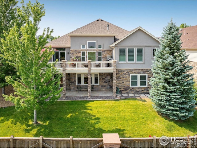 back of property with fence, stucco siding, a patio area, stone siding, and a lawn