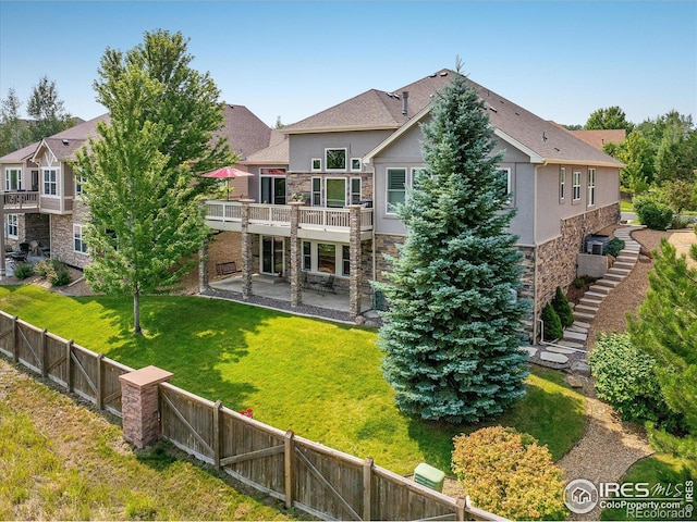 back of house featuring a patio area, stone siding, stucco siding, and a fenced backyard