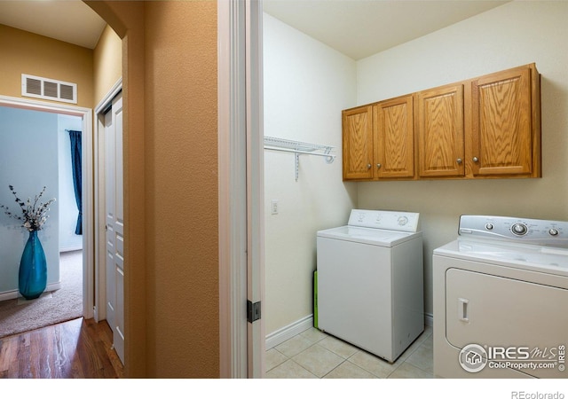 clothes washing area featuring baseboards, visible vents, cabinet space, arched walkways, and washing machine and dryer