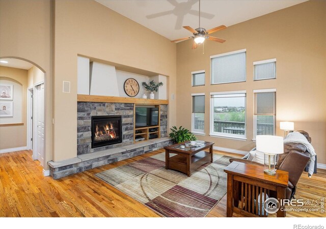 13943 W 87th Ln, Arvada, CO 80005 - living room with a ceiling fan, a fireplace, wood finished floors, arched walkways, and baseboards