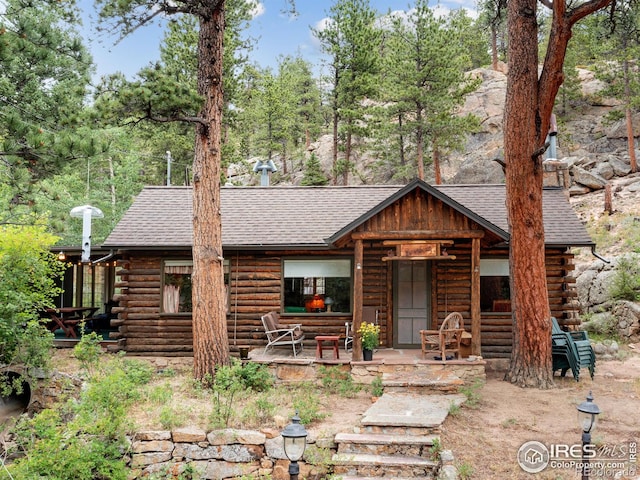 log-style house with log exterior and a shingled roof