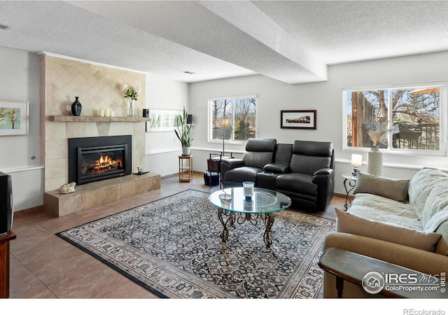 living area featuring tile patterned flooring, baseboards, a textured ceiling, and a tile fireplace