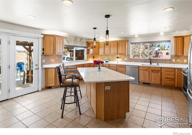 kitchen with a center island, light countertops, light tile patterned flooring, a sink, and dishwasher