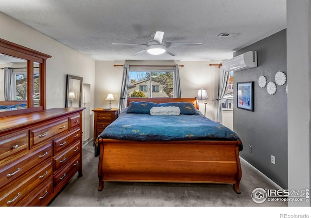 bedroom with a ceiling fan, carpet, a wall unit AC, and a textured ceiling