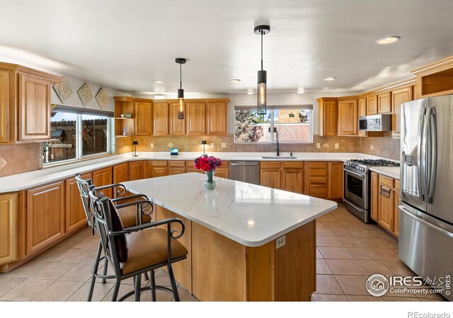 kitchen featuring decorative backsplash, a kitchen island, stainless steel appliances, open shelves, and a sink