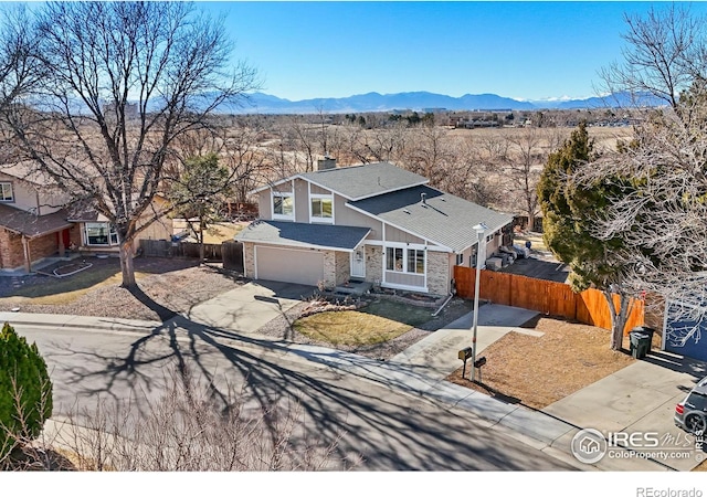 traditional-style home featuring an attached garage, fence, a mountain view, and concrete driveway