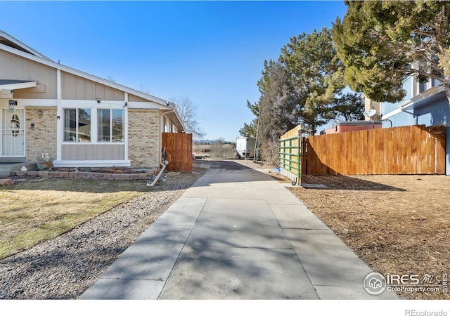 view of property exterior with board and batten siding, brick siding, and fence