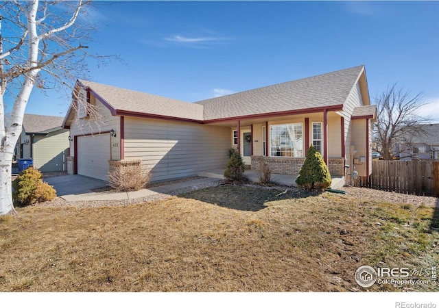 ranch-style home with a shingled roof, an attached garage, covered porch, fence, and brick siding