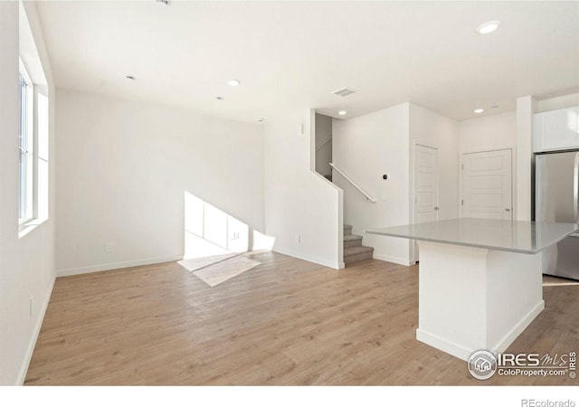 interior space with light wood finished floors, recessed lighting, visible vents, baseboards, and stairs