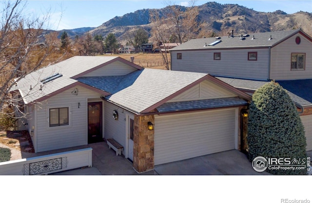 view of front facade with aphalt driveway, roof with shingles, an attached garage, and a mountain view