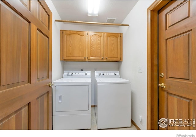 clothes washing area featuring washer and dryer, cabinet space, and visible vents