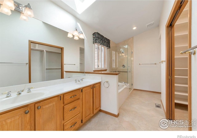 bathroom featuring a skylight, a shower with door, double vanity, a bathing tub, and a sink