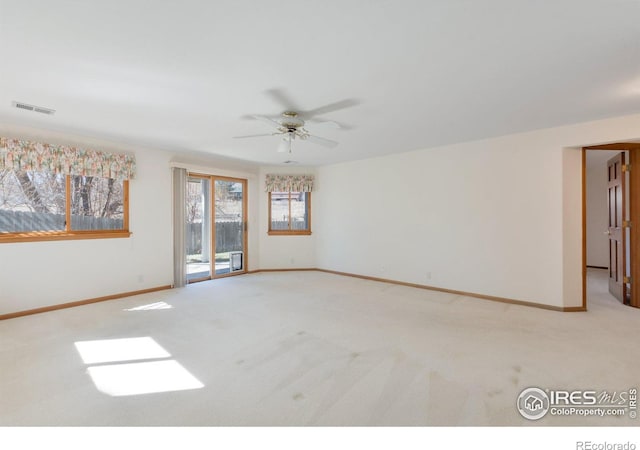 carpeted empty room featuring visible vents, a ceiling fan, and baseboards