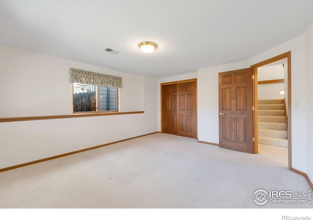 unfurnished bedroom with light carpet, baseboards, visible vents, and a closet