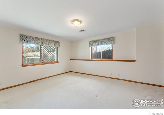 carpeted spare room featuring visible vents and baseboards