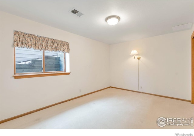 empty room featuring light carpet, visible vents, and baseboards