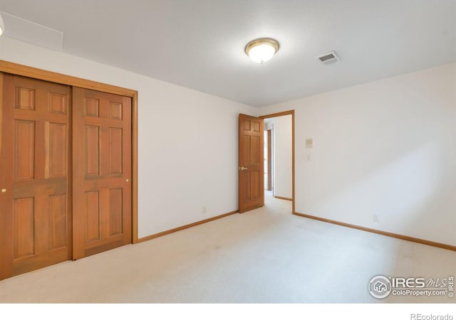 unfurnished bedroom featuring baseboards, visible vents, a closet, and light colored carpet