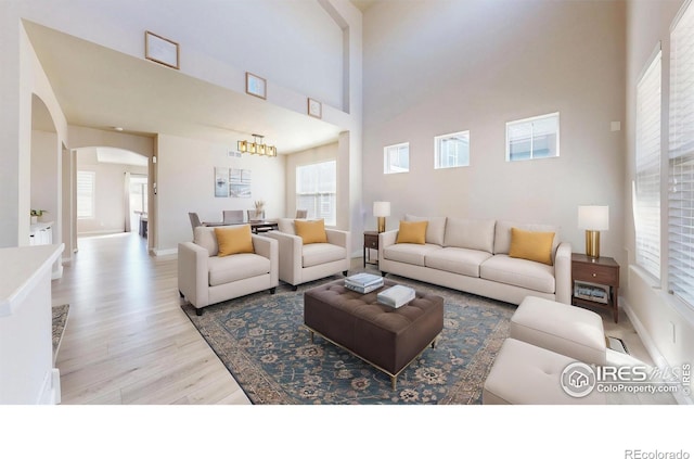 living room featuring arched walkways, a high ceiling, wood finished floors, and baseboards