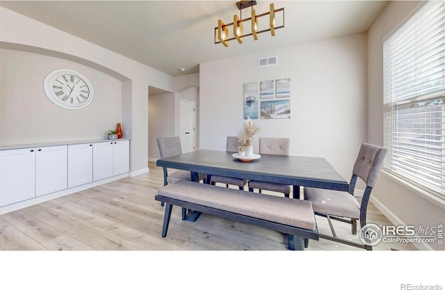 dining space with baseboards, visible vents, and light wood finished floors