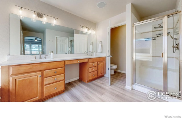 full bath featuring double vanity, a stall shower, a sink, and toilet