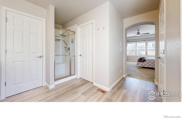 ensuite bathroom featuring visible vents, a shower stall, baseboards, and wood finished floors