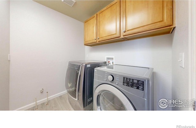 clothes washing area with visible vents, baseboards, light wood-type flooring, cabinet space, and washer and clothes dryer