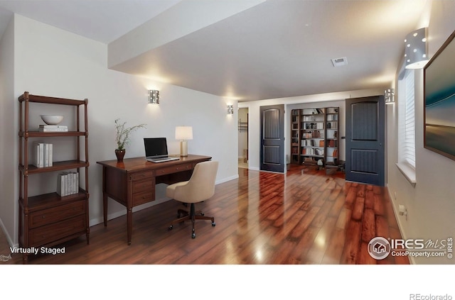 office space with baseboards, visible vents, and wood finished floors