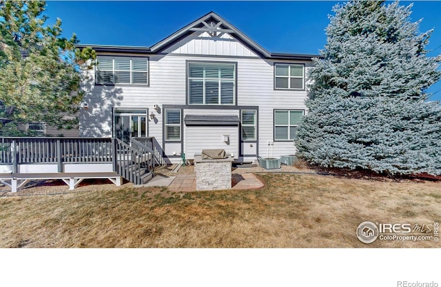 rear view of house with a lawn, cooling unit, a wooden deck, a patio area, and board and batten siding