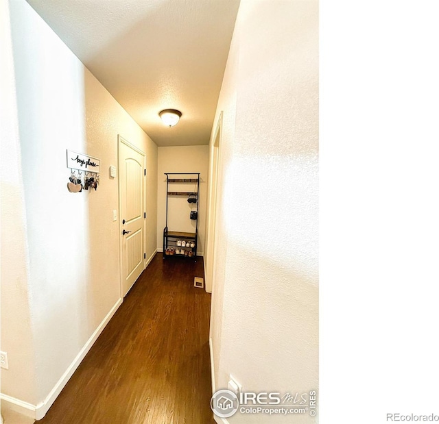 hallway with dark wood-type flooring, visible vents, and baseboards