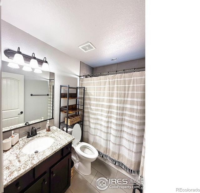 bathroom with a textured ceiling, a textured wall, tile patterned flooring, vanity, and visible vents