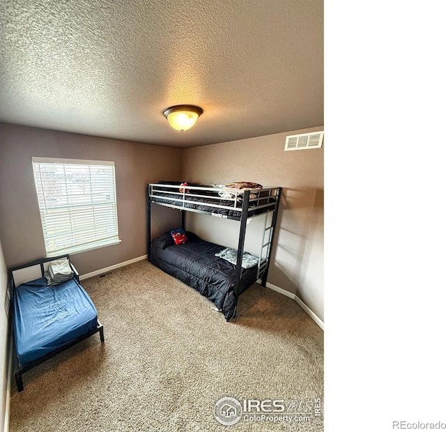 carpeted bedroom featuring baseboards, visible vents, and a textured ceiling