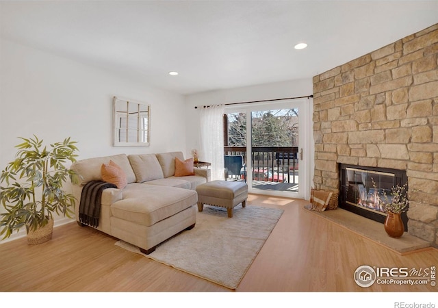 living room featuring a stone fireplace, wood finished floors, and recessed lighting