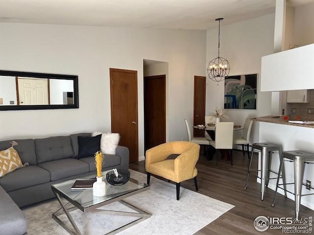 living room with high vaulted ceiling, wood finished floors, and an inviting chandelier