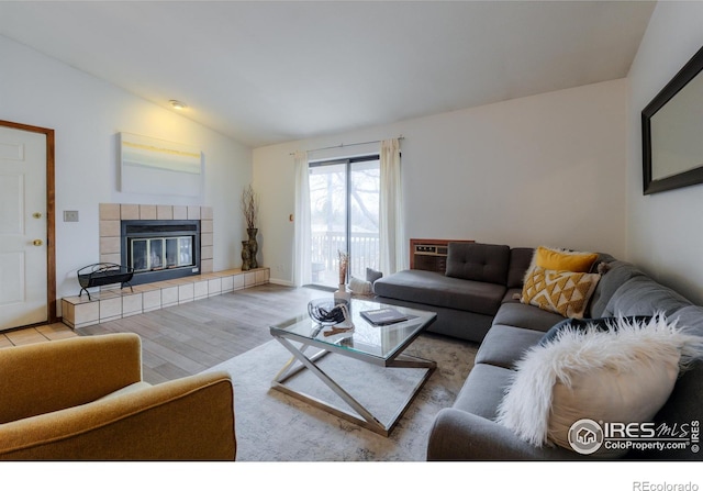 living room with lofted ceiling, wood finished floors, and a tile fireplace