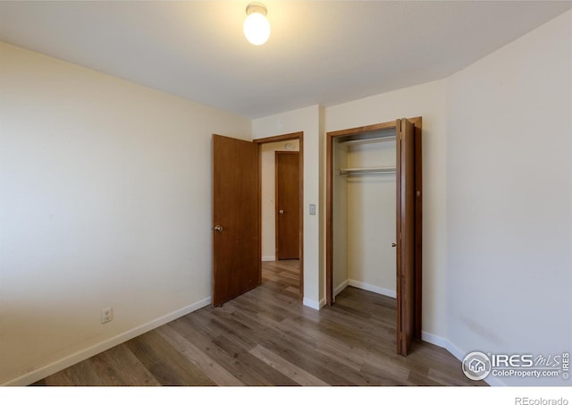 unfurnished bedroom with a closet, wood finished floors, and baseboards