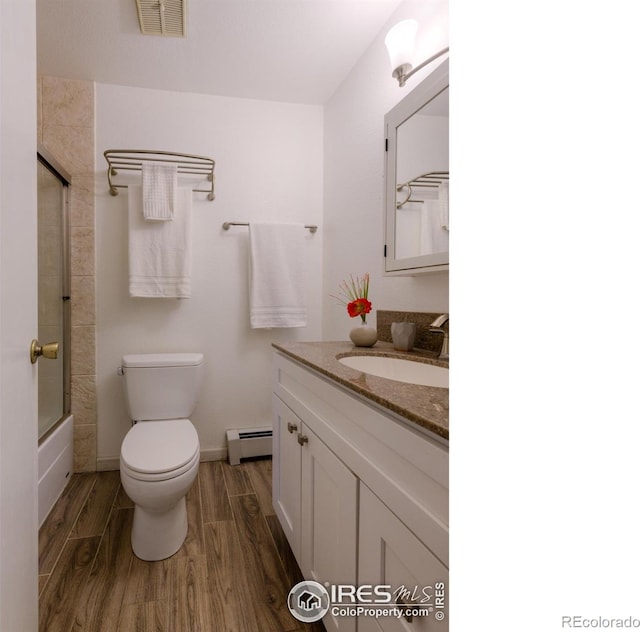 bathroom featuring visible vents, toilet, wood finished floors, vanity, and a baseboard heating unit