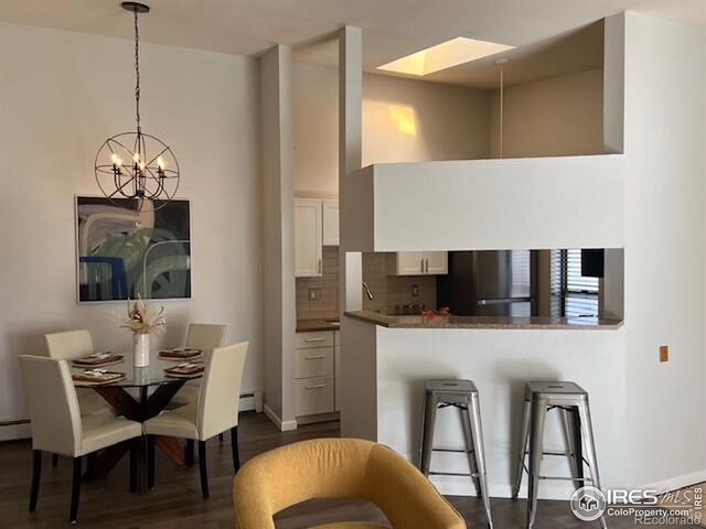 kitchen with dark wood-style floors, hanging light fixtures, baseboard heating, decorative backsplash, and white cabinets