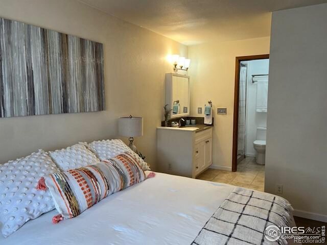 bedroom with a sink, light tile patterned floors, baseboards, and connected bathroom