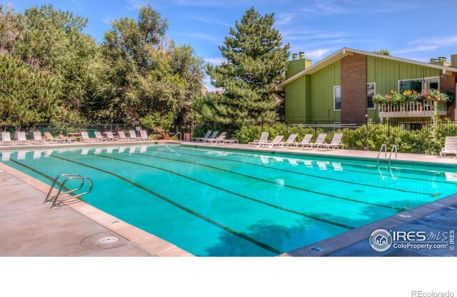 community pool with a patio and fence