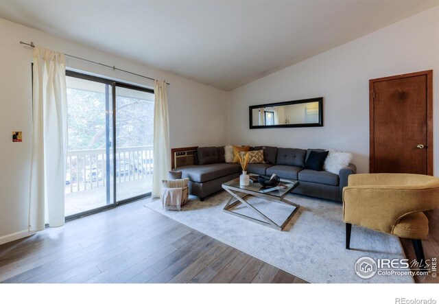 living area with vaulted ceiling and wood finished floors