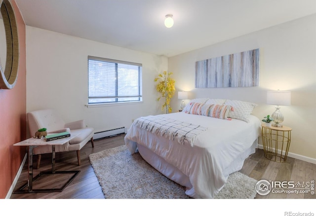 bedroom featuring a baseboard radiator, baseboards, and wood finished floors