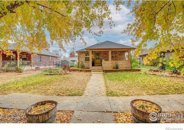 bungalow featuring covered porch, brick siding, and a front lawn