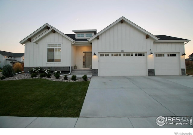 view of front of home featuring board and batten siding, concrete driveway, a lawn, and a garage