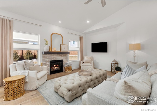 living room featuring lofted ceiling, a brick fireplace, light wood finished floors, and recessed lighting