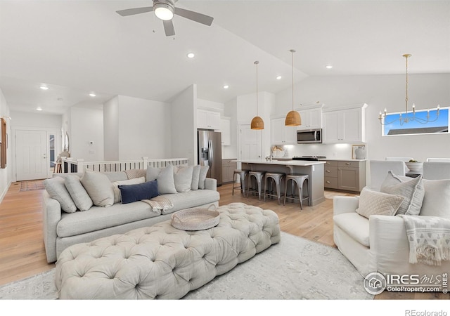 living area with light wood-type flooring, recessed lighting, high vaulted ceiling, and ceiling fan with notable chandelier