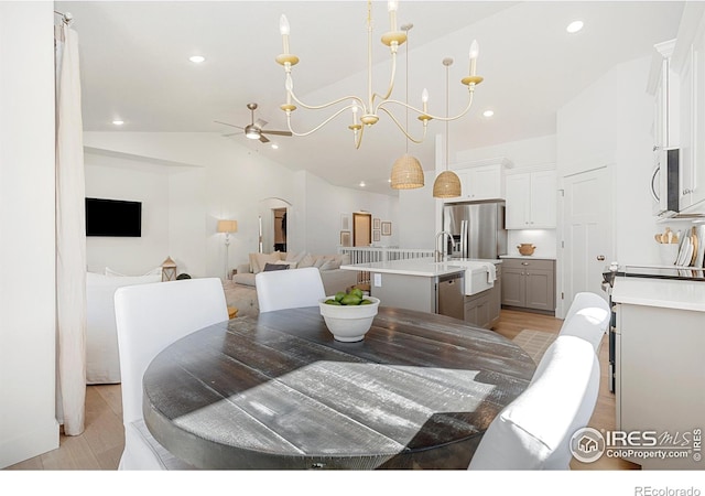 dining space featuring ceiling fan with notable chandelier, high vaulted ceiling, light wood-style floors, and recessed lighting