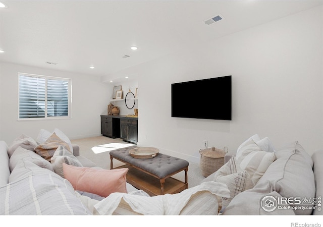 living area featuring baseboards, recessed lighting, visible vents, and light colored carpet